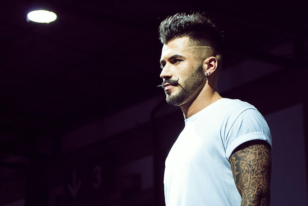 A man with a fade, a cut line at the side and a trimmed beard, seen in profile