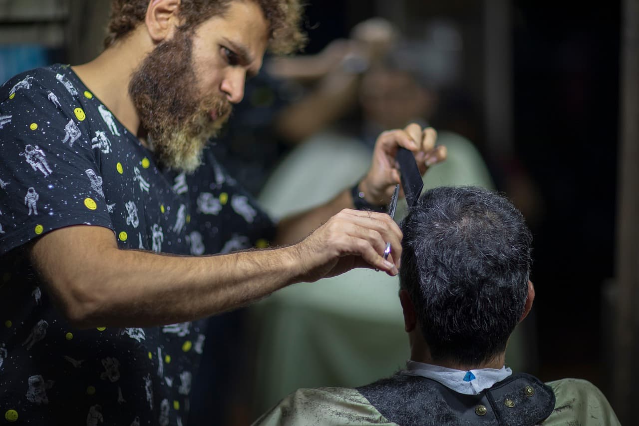A barber running clippers up the back of a customer's head