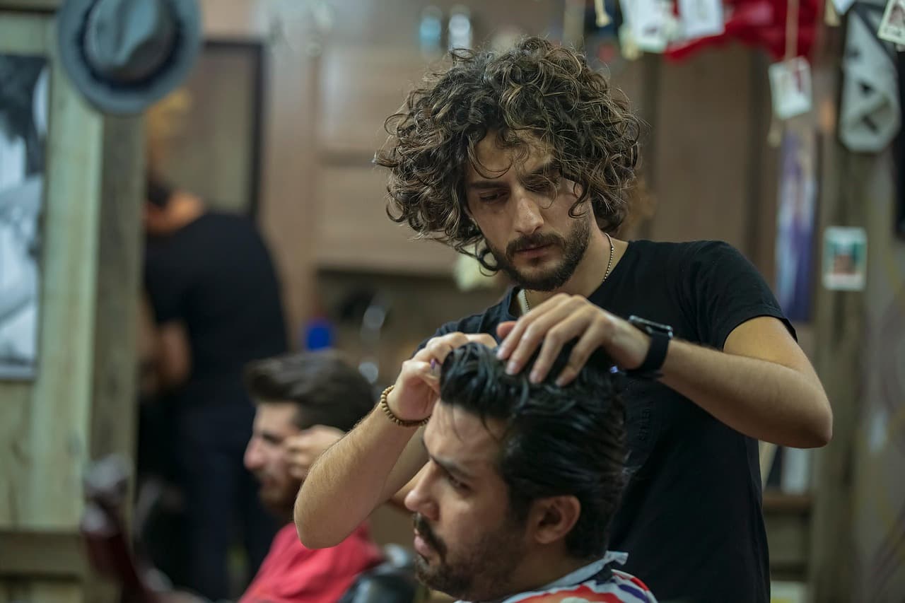 A barber working through a customer's hair with his fingers before the cut